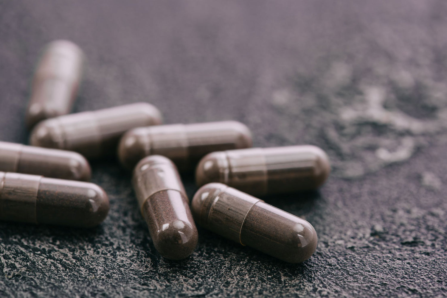 Capsules on a grey industrial surface in a supplement manufacturing facility
