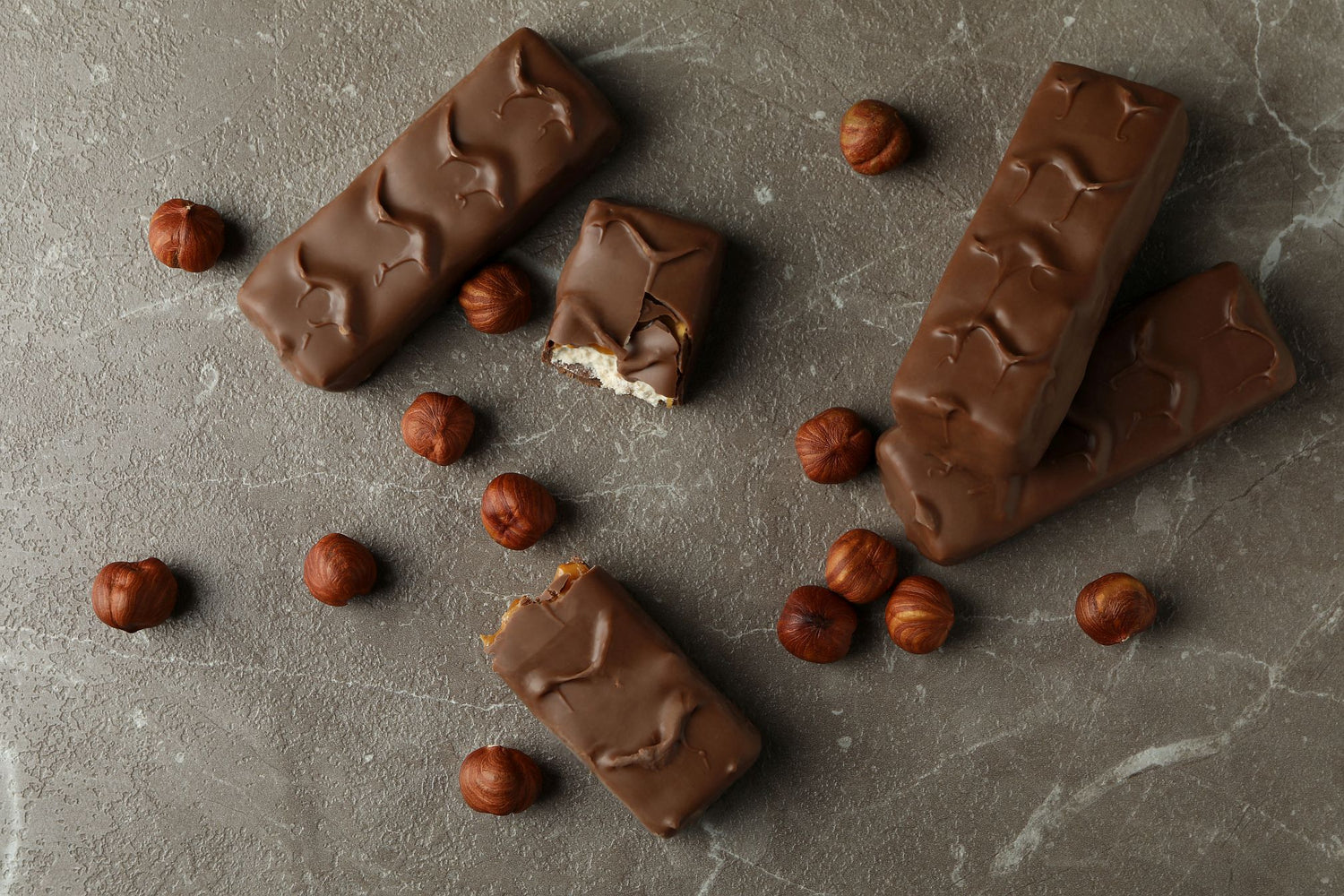 Private label protein bars and nuts on a grey textured surface